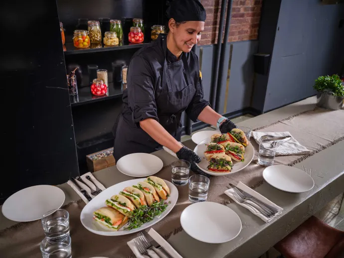 Chef placing plate of sandwiches on table